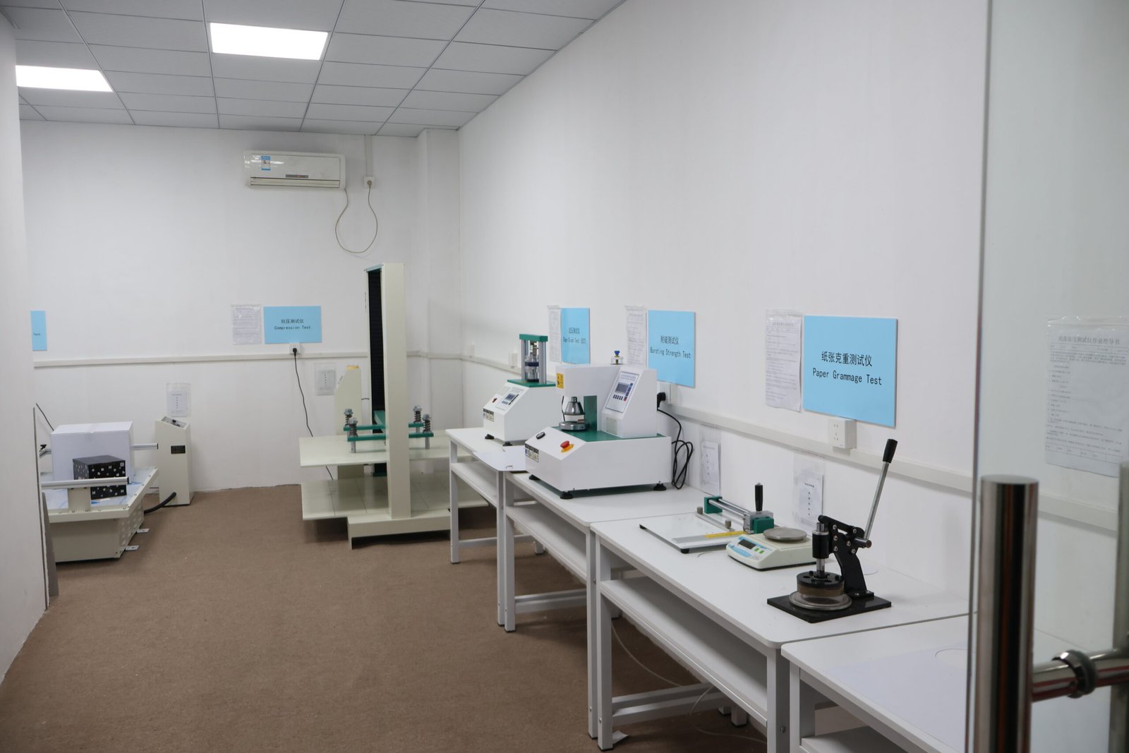 A person performing a drop test on a packaged box in a warehouse setting.