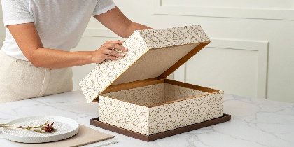 a person slowly lifting the lid off a beautiful two-piece rigid box to reveal a product inside