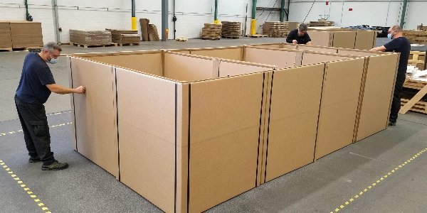 Large sheets of cardboard being assembled into a very big box