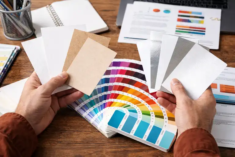 A designer looking at various paperboard samples and color swatches